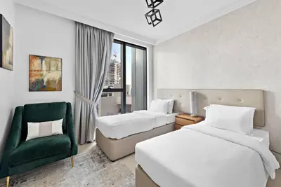 a hotel room with two beds and a green chair at Modern 2BR with Harbor Views, Pool, & Concierge in Dubai