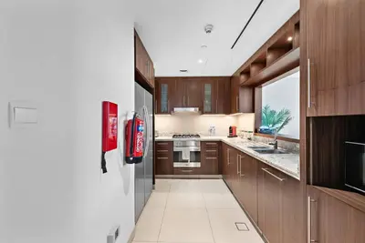 a kitchen with wooden cabinets and a refrigerator at Modern 2BR with Harbor Views, Pool, & Concierge in Dubai