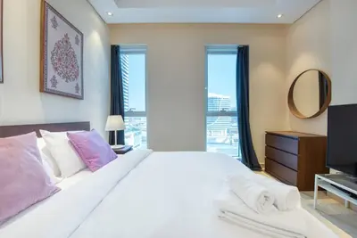 a bedroom with a large white bed and a mirror at 1BR + maid room Apartment in Downtown Dubai in Dubai