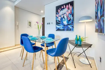 a dining room with a glass table and blue chairs at 1BR + maid room Apartment in Downtown Dubai in Dubai