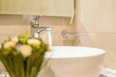 a bathroom sink with a faucet and a vase of flowers at Elegant Studio at Aykon City Tower - C in Dubai