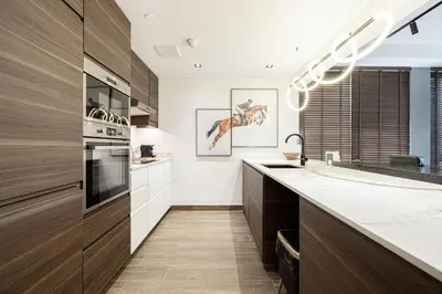 a kitchen with white counters and wooden cabinets at The Signature Burj Khalifa View Residence with Terrace in Dubai
