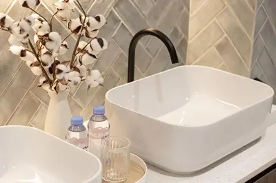 a white sink and a vase with flowers on a counter at The Signature Burj Khalifa View Residence with Terrace in Dubai