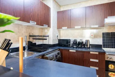 a kitchen with wooden cabinets and a counter top at Stylish 1 BR in The Medalist by PK Holidays in Dubai