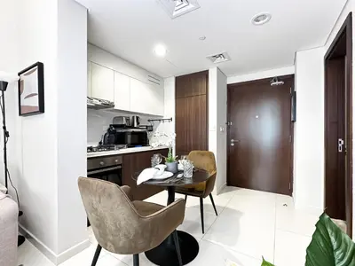 a kitchen with a table and chairs in a room at Trophy - Blossom Suites w Balcony Garden & Canal View in Dubai