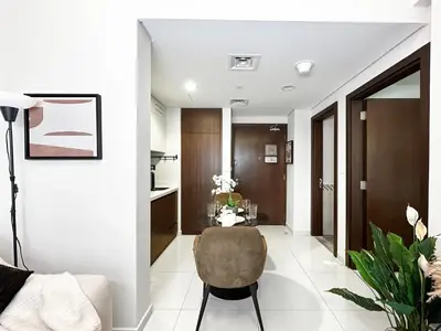 a living room with a chair and a table at Trophy - Blossom Suites w Balcony Garden & Canal View in Dubai
