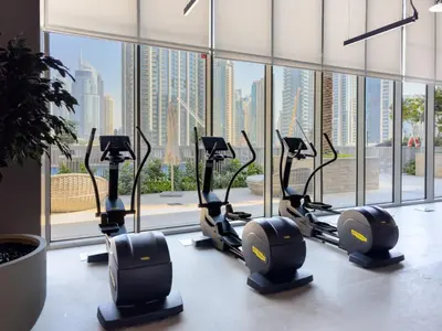 a row of treadmills in a gym with a window at Charming Apartment in Downtown Just Steps from Burj Khalifa & Dubai Mall by Bhavan Vacation Homes in Dubai