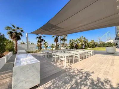 a patio with white tables and chairs under a large umbrella at Remarkable 2BR+storage in JBR with Sea View in Dubai