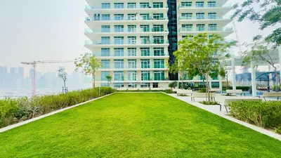 a green lawn in front of a tall building at Marina Skyline View & Dubai Harbour Beachfront in Dubai