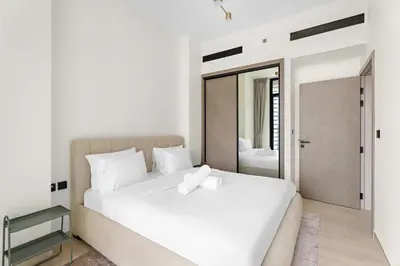 a white bedroom with a white bed and a mirror at Stunning modern 3BR apartment in JVC in Dubai