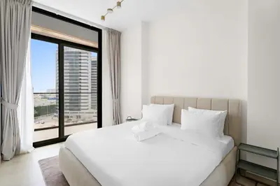 a bedroom with a large white bed and a large window at Stunning modern 3BR apartment in JVC in Dubai