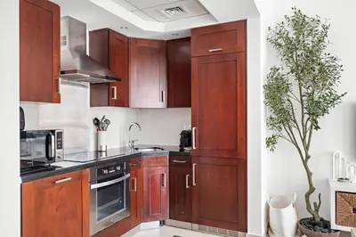 a kitchen with wooden cabinets and a potted plant at Silkhaus Modern Studio Near Burj Khalifa in Dubai