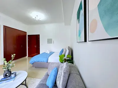 a living room with a couch and a bed at Lxury Brand New Studio w/ Balcony and Marina View in Dubai