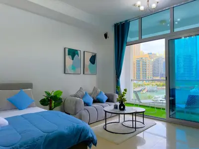 a bedroom with a blue bed and a couch at Lxury Brand New Studio w/ Balcony and Marina View in Dubai
