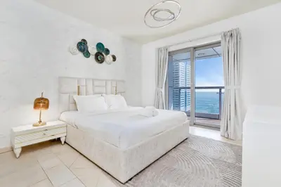 a white bedroom with a large bed and a large window at Ahlan HH - Princess Tower - Elegant 1BR in Dubai Marina in Dubai
