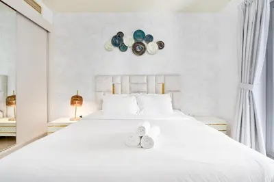 a white bedroom with a white bed with two shoes on it at Ahlan HH - Princess Tower - Elegant 1BR in Dubai Marina in Dubai
