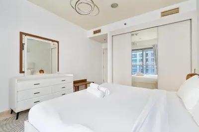 a white bedroom with a large mirror and a bed at Ahlan HH - Princess Tower - Elegant 1BR in Dubai Marina in Dubai