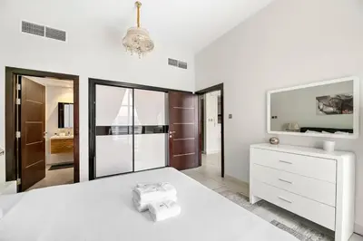 a white bedroom with a white bed and a mirror at StoneTree - Furnished 1 BR - Glitz 3 in Dubai