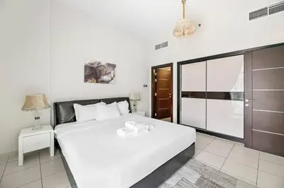 a bedroom with a white bed and a sliding glass door at StoneTree - Furnished 1 BR - Glitz 3 in Dubai