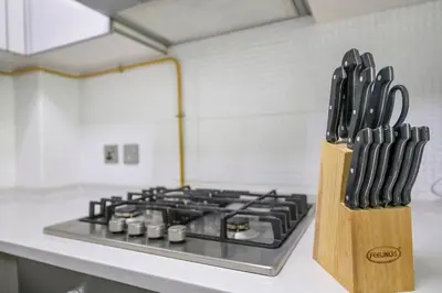 a kitchen counter with a knife block with a stove at StoneTree - Furnished 1 BR - Glitz 3 in Dubai