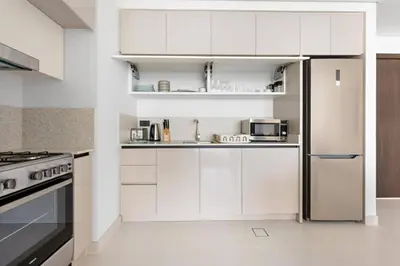 a kitchen with white cabinets and a refrigerator at Your Private Beach Sunny Retreat in Dubai