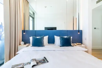 a bedroom with a large bed with a blue headboard at FIRST CLASS 1BR High Floor with Magical View in Dubai