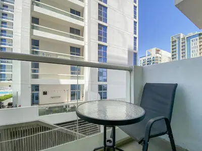 a table and a chair on a balcony with a window at Cozy Studio in Al Furjan in Dubai