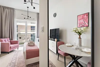 a living room with a table and a pink chair at Cozy Studio in Al Furjan in Dubai