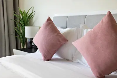 two pink pillows on a bed with white pillows at Cozy Studio in Al Furjan in Dubai