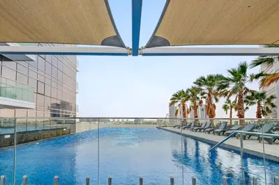 a view of a swimming pool in a building with palm trees at Comfortable Studio in Damac Hills in Dubai