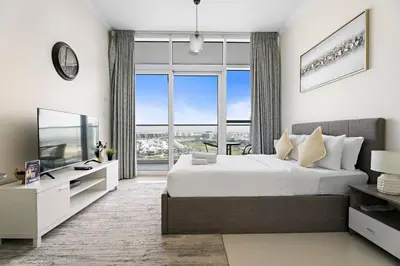 a bedroom with a large bed and a large window at Comfortable Studio in Damac Hills in Dubai