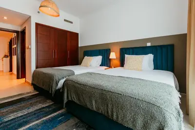 two beds in a hotel room with blue curtains at Stylish 2-Bedroom Escape near Dubai Mall in Dubai