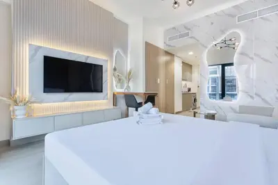 a white living room with a television and a living room at Tranquil Studio Retreat in Azizi 34 Near Downtown in Dubai