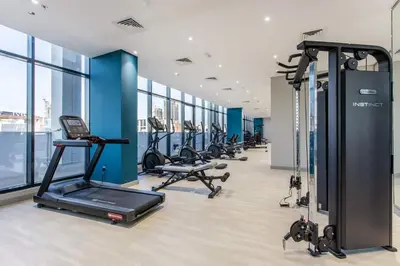 a gym with a row of treadmills and ellipticals at Tranquil Studio Retreat in Azizi 34 Near Downtown in Dubai