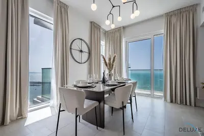 a dining room with a table and chairs and a large window at Elegant 2BR Apartment in La Vie, JBR by Deluxe Holiday Homes in Dubai