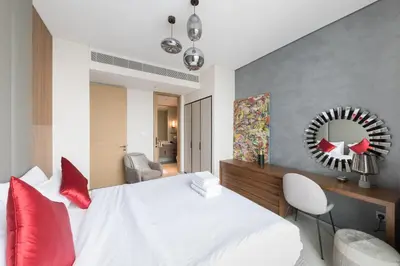 a bedroom with a white bed with red pillows and a mirror at Fabulous 1BR apartment in Address Beach Resort in Dubai