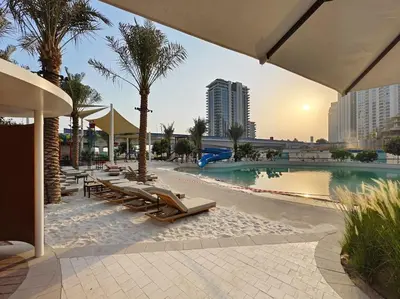 a resort with a pool with lounge chairs and palm trees at Creek Beachfront Heaven: 1BR Luxe Harbor Flat in Dubai