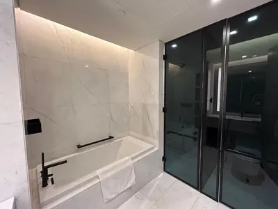 a bathroom with a bath tub and a glass shower at Bluewaters Island - Modern 2 bedroom Full Apartment in Dubai
