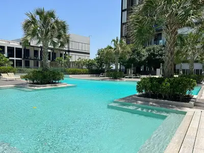 a large blue pool with palm trees and a building at Bluewaters Island - Modern 2 bedroom Full Apartment in Dubai