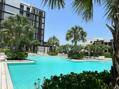 a large swimming pool with palm trees and a building at Bluewaters Island - Modern 2 bedroom Full Apartment in Dubai
