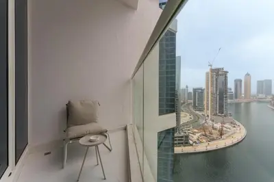 a chair on a balcony with a view of the city at Your Dream Home in Damac Maison Prive by Suiteable in Dubai