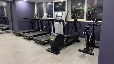 a gym with a row of treadms and elliptical machines at Newly renovated cosy studio in Dubai
