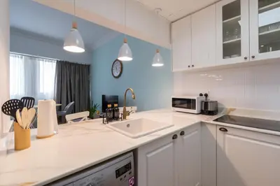 a kitchen with white cabinets and a sink and a microwave at Newly renovated cosy studio in Dubai