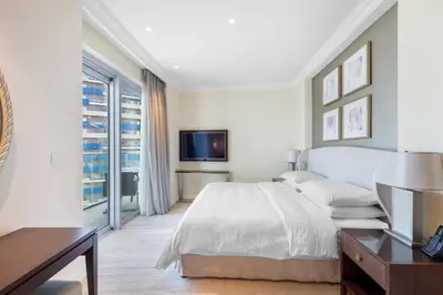 a white bedroom with a bed and a tv at The Address Fountain Views - Residence 2 Bedroom with Burj Khalifa view in Dubai