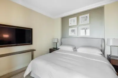 a bedroom with a white bed and a flat screen tv at The Address Fountain Views - Residence 2 Bedroom with Burj Khalifa view in Dubai