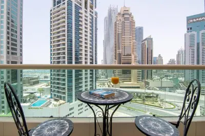 a table and chairs on a balcony with a view of a city at Stylish 1BR Apartment with City View Balcony Pool and Parking in Dubai