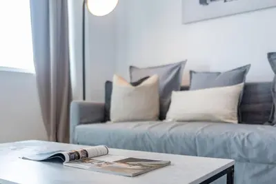 a living room with a couch and a table with a magazine at Stylish 1BR Apartment with City View Balcony Pool and Parking in Dubai