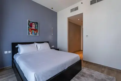 a bedroom with a large bed with a blue wall at Noora Tower I Habtoor City I Spacious 3BDR plus maid room I Business Bay in Dubai