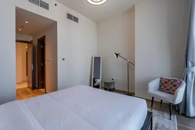 a bedroom with a white bed and a chair at Noora Tower I Habtoor City I Spacious 3BDR plus maid room I Business Bay in Dubai