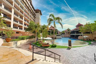 a resort swimming pool with palm trees and a building at FIRST CLASS 1BR in Royale Apartment on the Palm in Dubai